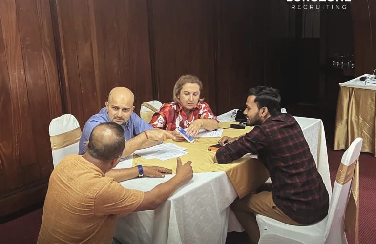 Four colleagues around a table in a function room, working through candidate paperwork.